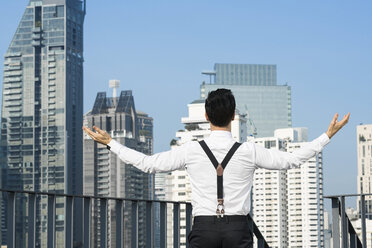 Happy and content successful business man on city rooftop - SBOF01539