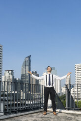 Happy and content successful business man on city rooftop - SBOF01540