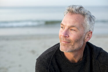 Porträt eines grauhaarigen Mannes, der allein am Küstenstrand sitzt und wegschaut, Dennis, Massachusetts, USA - AURF07235
