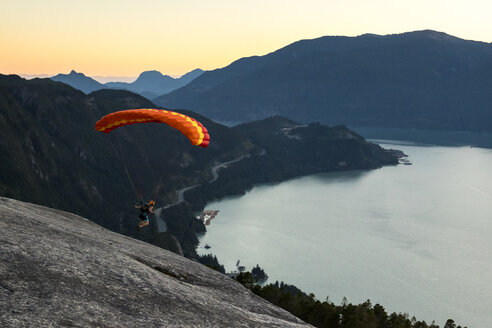 Person beim Gleitschirmfliegen über dem Howe Sound Fjord in der Abenddämmerung, Squamish, British Columbia, Kanada - AURF07241