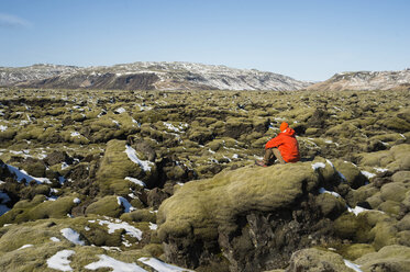 Person sitting alone on lava field, Iceland - AURF07248