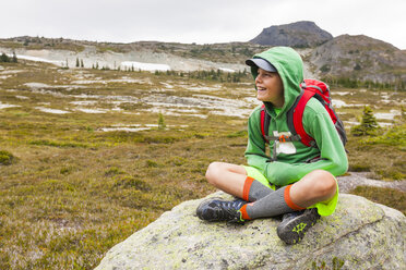 Portrait of young boy wearing backpack and sitting on stone, Merritt, British Columbia, Canada - AURF07255