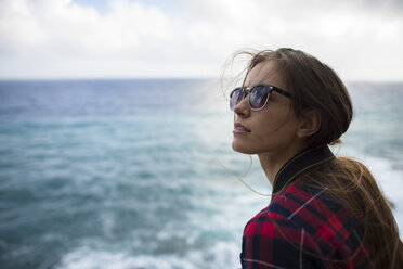 Porträt einer Frau mit braunem Haar und Sonnenbrille am Meer, Sardinien, Italien - AURF07279