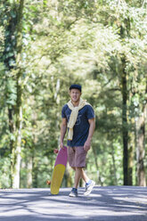 Porträt eines Mannes mit Skateboard auf der Straße, Bedugul, Bali, Indonesien - AURF07283