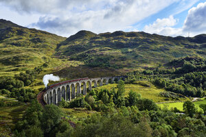 UK, Scotland, Highlands, Glenfinnan viaduct with a steam train passing over it - RUEF01997