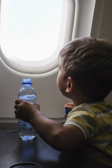 Kleiner Junge in einem Flugzeug schaut aus dem Fenster - MOMF00506
