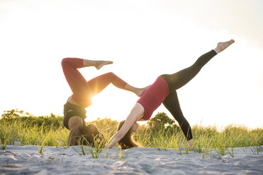 Zwei Frauen beim Yoga in der Assistierten Skorpionstellung (Pincha Mayurasana) und der Dreibeinigen Hundestellung (Eka Pada Adho Mukha Svanasana), Newport, Rhode Island, USA - AURF07370