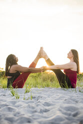 Two women doing yoga in Assisted Boat Pose (Navasana), Newport, Rhode Island, USA - AURF07371