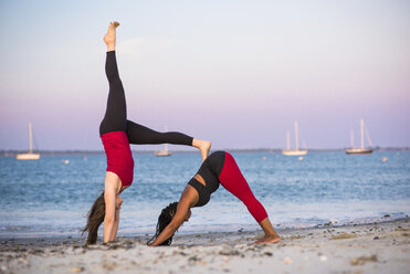 Zwei Frauen beim Yoga in Downward Facing Dog Pose und Assisted Handstand Pose, Newport, Rhode Island, USA - AURF07376