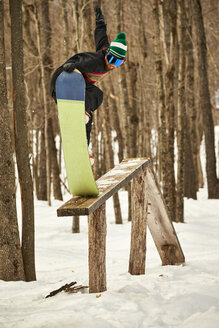 Snowboarder rutscht auf einer Holzkonstruktion in einem Geländepark, Vermont, USA - AURF07439