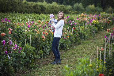 Smiling mother holding baby while standing in flower farm, Parkdale, Oregon, USA - AURF07450