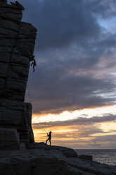 Silhouette eines Mannes beim Klettern bei Sonnenuntergang in Sardinien, Italien - AURF07485