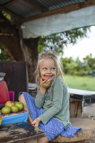 Lächelndes Mädchen isst Apfel, Nusa Penida, Bali, Indonesien, lizenzfreies Stockfoto