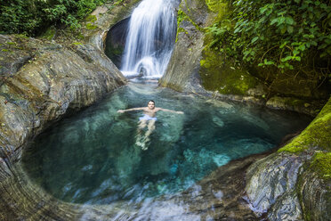 Landschaft mit einem Mann, der im Fluss des Atlantischen Regenwaldes schwimmt, Serrinha do Alambari, Staat Rio de Janeiro, Brasilien - AURF07540