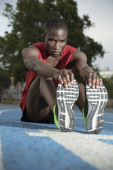 Runner stretching on sports track, Barcelona, Catalonia, Spain - AURF07564