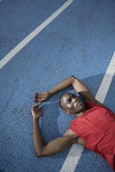 Runner lying while resting on sports track, Barcelona, Catalonia, Spain - AURF07565