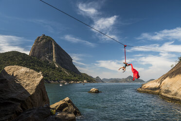 Frau macht Luftakrobatik an einem Hochseil neben dem Zuckerhut in Rio de Janeiro, Brasilien - AURF07578