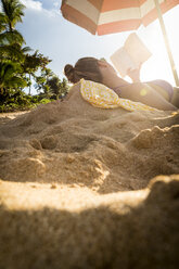 Woman in bikini reading book on beach, Oahu, Hawaii, USA - AURF07593