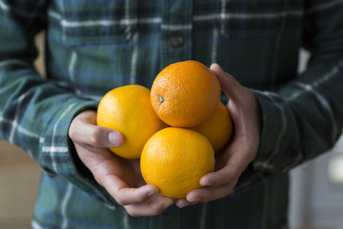 Man's hands holding four oranges, close-up - JUNF01298