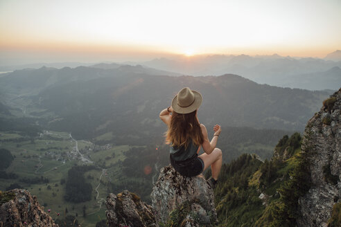 Schweiz, Grosse Mythen, junge Frau auf Wanderschaft, sitzend auf einem Felsen bei Sonnenaufgang - LHPF00038