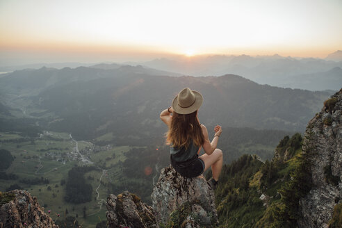 Switzerland, Grosser Mythen, young woman on a hiking trip sitting on a rock at sunrise - LHPF00038