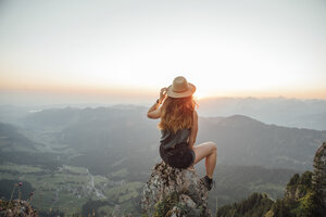 Schweiz, Grosse Mythen, junge Frau auf Wanderschaft, sitzend auf einem Felsen bei Sonnenaufgang - LHPF00040