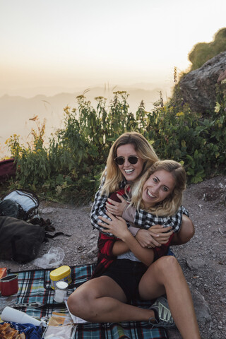 Schweiz, Grosse Mythen, zwei glückliche Freundinnen auf einer Wandertour mit Picknickpause bei Sonnenaufgang, lizenzfreies Stockfoto