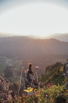 Schweiz, Grosse Mythen, junge Frau auf Wanderschaft, sitzend auf einem Felsen bei Sonnenaufgang - LHPF00048