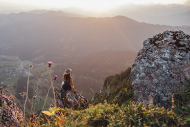 Schweiz, Grosse Mythen, junge Frau auf Wanderschaft, sitzend auf einem Felsen bei Sonnenaufgang - LHPF00049