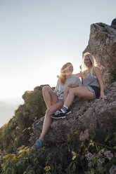 Schweiz, Grosse Mythen, zwei glückliche Freundinnen auf einer Wanderung machen bei Sonnenaufgang eine Pause - LHPF00050