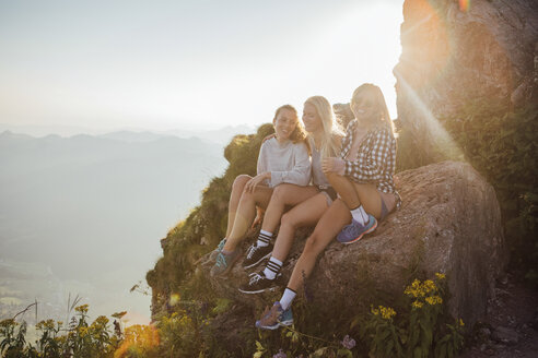 Schweiz, Grosse Mythen, drei glückliche Freundinnen auf einer Wanderung machen bei Sonnenaufgang eine Pause - LHPF00052