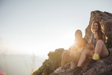 Schweiz, Grosse Mythen, zwei glückliche Freundinnen auf einer Wanderung machen bei Sonnenaufgang eine Pause - LHPF00055