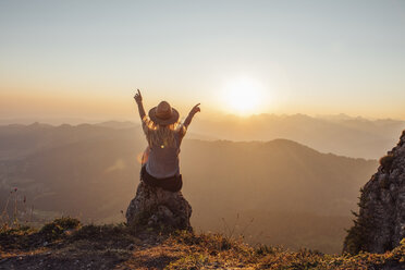 Schweiz, Grosse Mythen, junge Frau auf Wanderschaft, sitzend auf einem Felsen bei Sonnenaufgang - LHPF00060