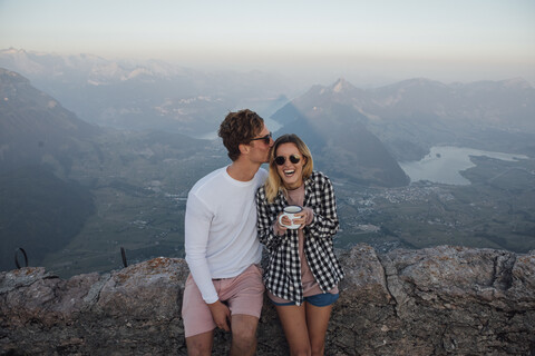 Switzerland, Grosser Mythen, happy young couple on a hiking trip having a break at sunrise stock photo
