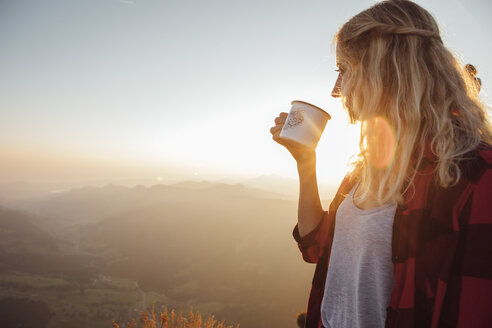 Schweiz, Grosse Mythen, junge Frau auf einer Wanderung bei Sonnenaufgang mit einer Tasse in der Hand - LHPF00070