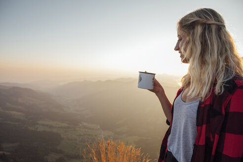 Schweiz, Grosse Mythen, junge Frau auf einer Wanderung bei Sonnenaufgang mit einer Tasse in der Hand - LHPF00071