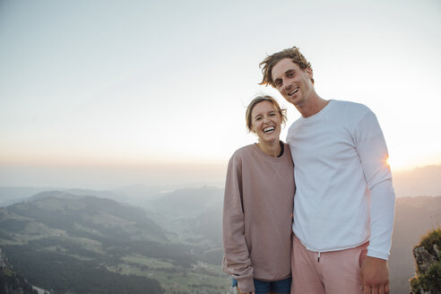 Schweiz, Grosser Mythen, Porträt eines glücklichen jungen Paares in einer Berglandschaft bei Sonnenaufgang - LHPF00077