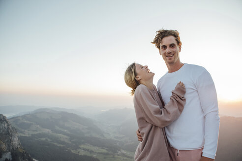 Schweiz, Grosser Mythen, Porträt eines glücklichen jungen Paares in einer Berglandschaft bei Sonnenaufgang - LHPF00079