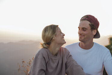 Glückliches junges Paar auf einem Wanderausflug macht bei Sonnenaufgang eine Pause - LHPF00083