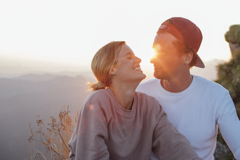 Glückliches junges Paar auf einem Wanderausflug macht bei Sonnenaufgang eine Pause - LHPF00084