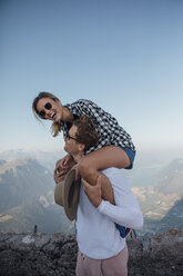 Switzerland, Grosser Mythen, happy young man carrying girlfriend piggyback - LHPF00087