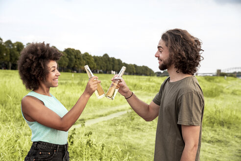 Glückliches Paar stößt mit Bierflaschen in der Natur an - FMKF05262