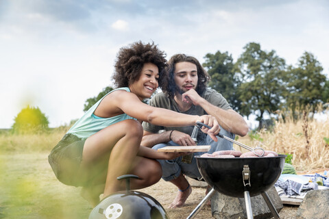 Glückliches Paar beim Grillen in der Natur, lizenzfreies Stockfoto