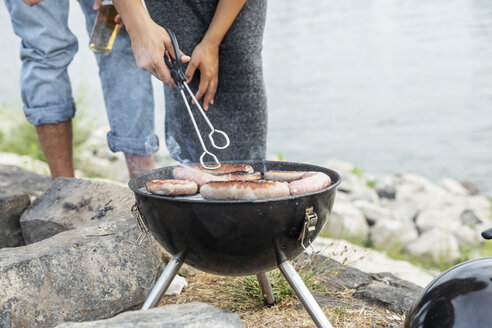 Nahaufnahme eines Paares beim Grillen am Flussufer - FMKF05282