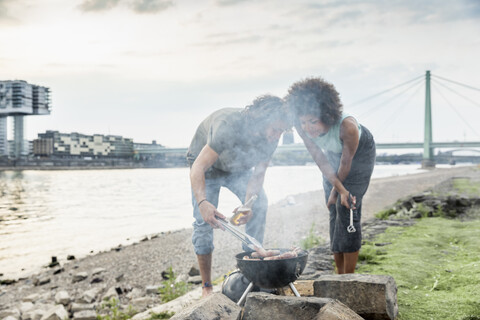 Deutschland, Köln, Paar beim Grillen am Flussufer, lizenzfreies Stockfoto