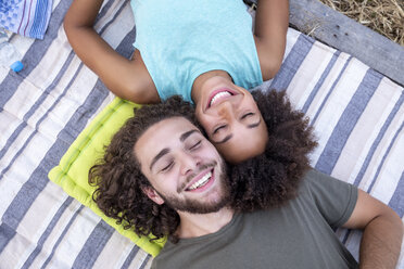 Happy couple with closed eyes lying on a blanket outdoors - FMKF05284
