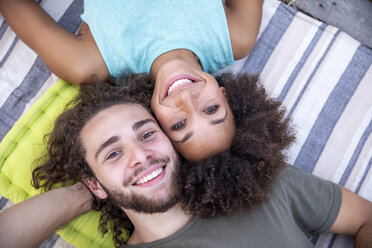 Portrait of happy couple lying on a blanket outdoors - FMKF05285