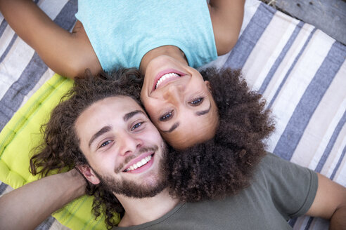 Porträt eines glücklichen Paares auf einer Decke liegend im Freien - FMKF05285