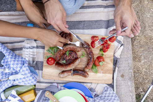 Nahaufnahme eines Paares, das draußen Bratwürste und Tomaten isst - FMKF05287