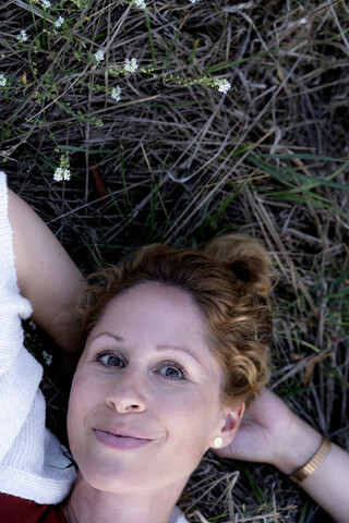 Porträt einer lächelnden Frau, die auf dem Boden liegt, lizenzfreies Stockfoto